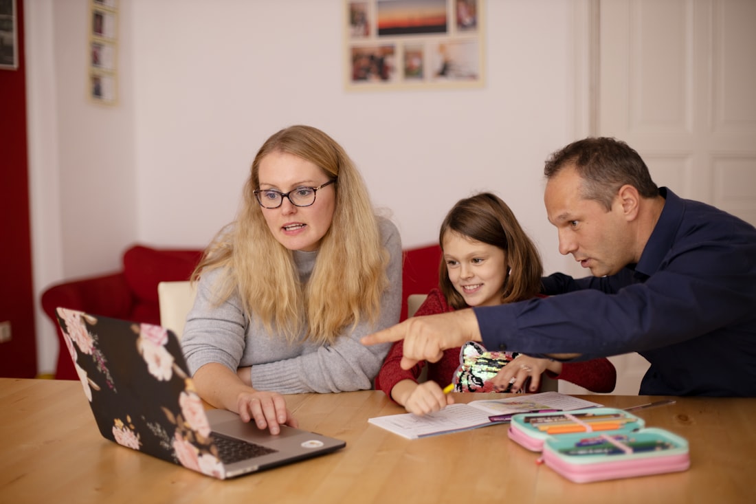 A mother and father reviewing schoolwork on a laptop with their child